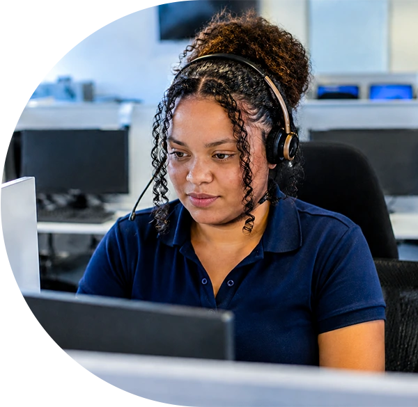 SkyHigh Global call centre agent wearing a headset and navy polo shirt, working at a computer workstation